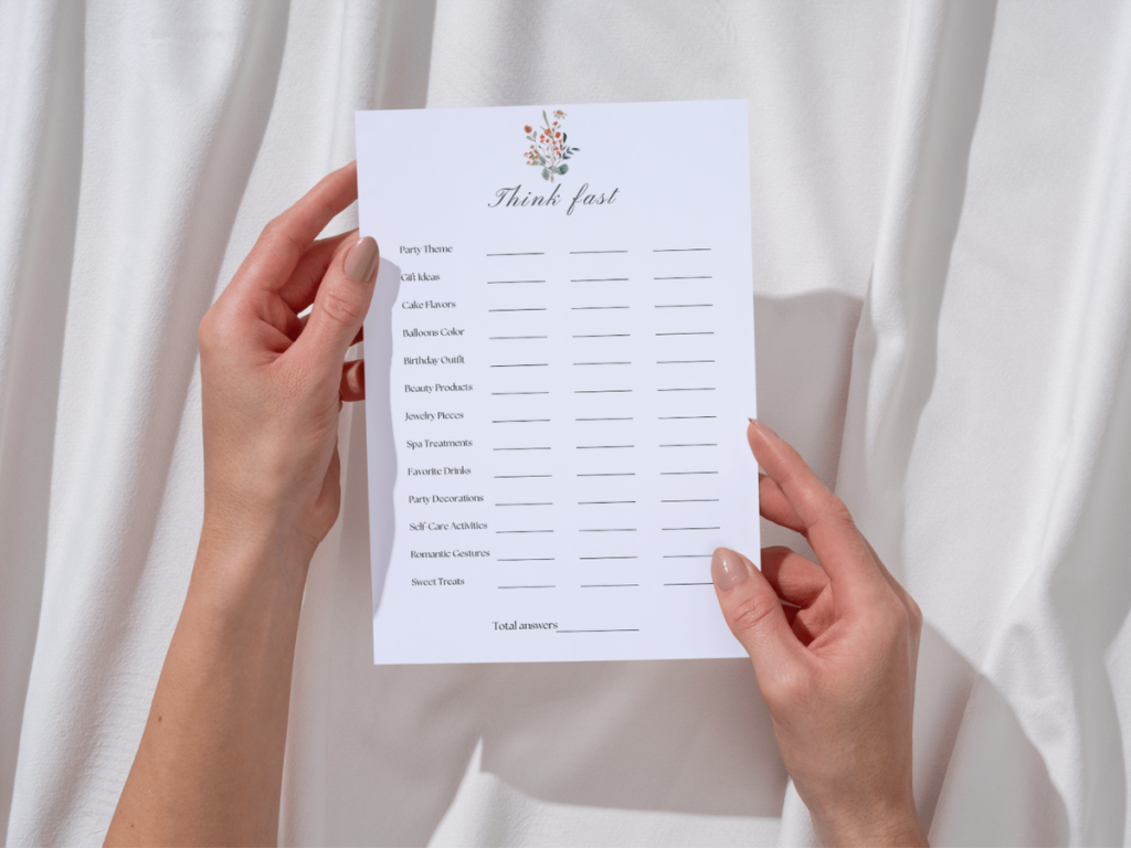 A person holds a beautifully designed printable game sheet titled "Think Fast" on a soft white fabric background. The sheet includes fun categories like party themes and gift ideas. This image represents the ease of enjoying printable games and is perfect for our How To Print Free Printable Games guide, helping you get the best results for screen-free fun!