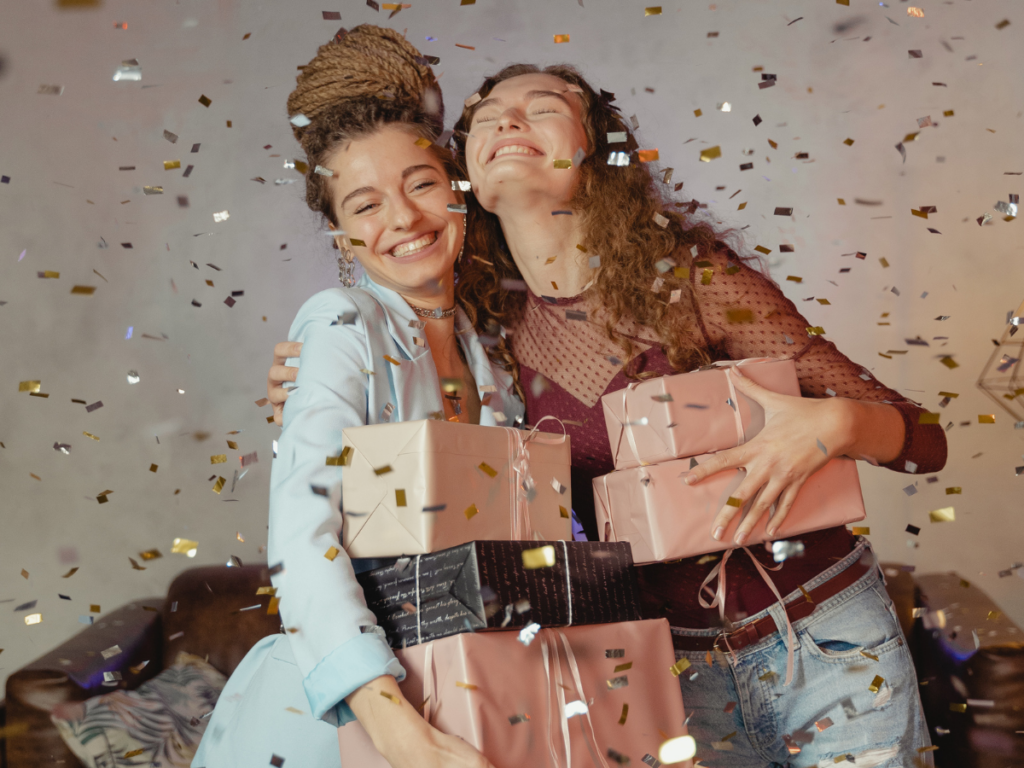 Two women celebrating with wrapped gifts and confetti, symbolizing the joy and connection created through printable games and free printable games for all occasions.