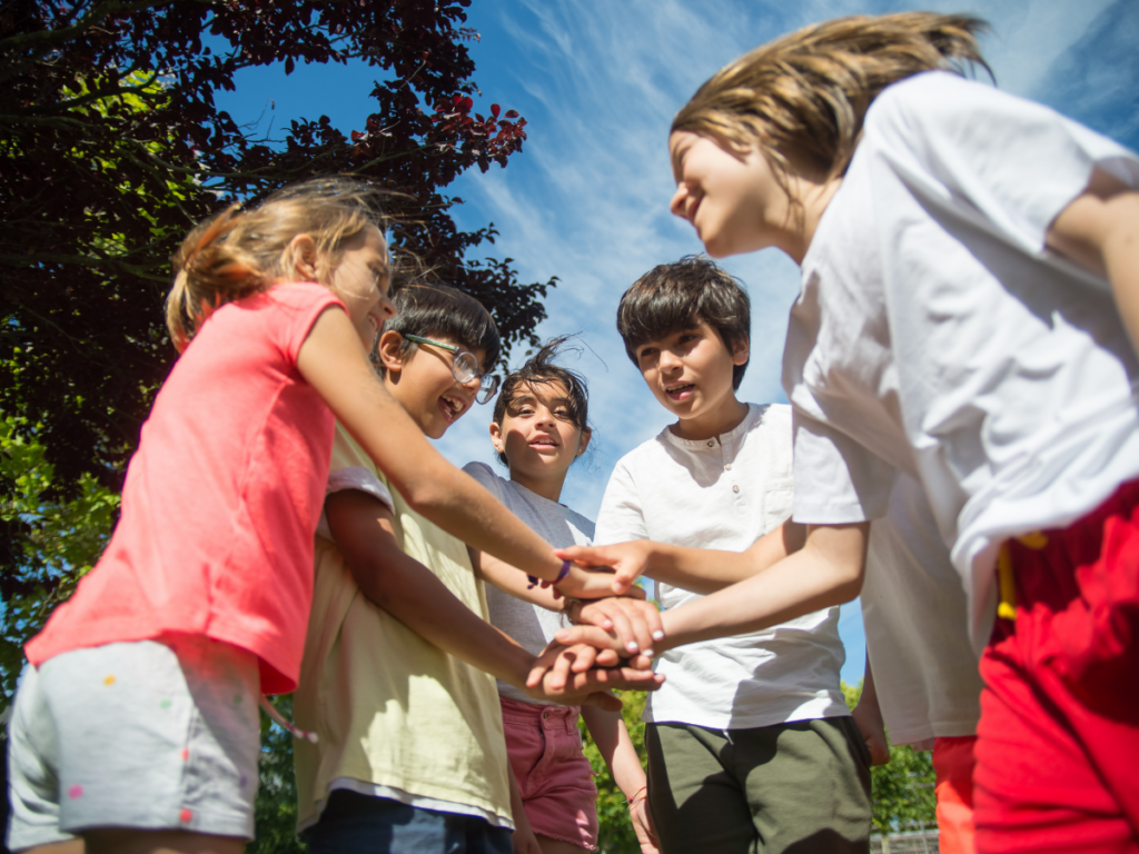 Children playing a group game outdoors in a circle, laughing and bonding during a screen-free activity.