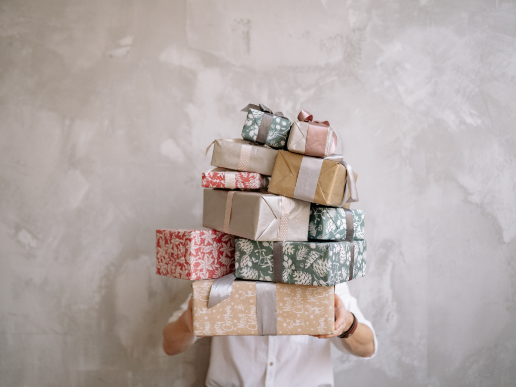 Person holding a tall stack of beautifully wrapped gifts, symbolizing the variety and joy of receiving free printable games for screen-free fun and connection.