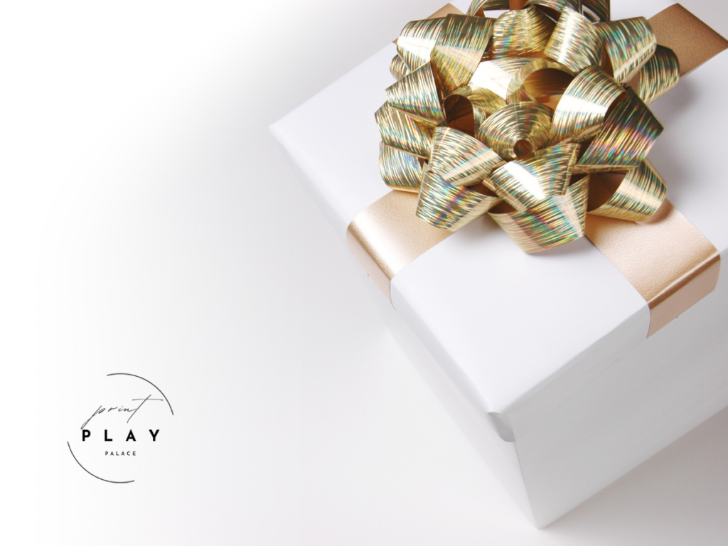 Elegant white gift box with gold ribbon and PrintPlayPalace logo, representing the excitement of receiving free printable games for screen-free fun and connection.