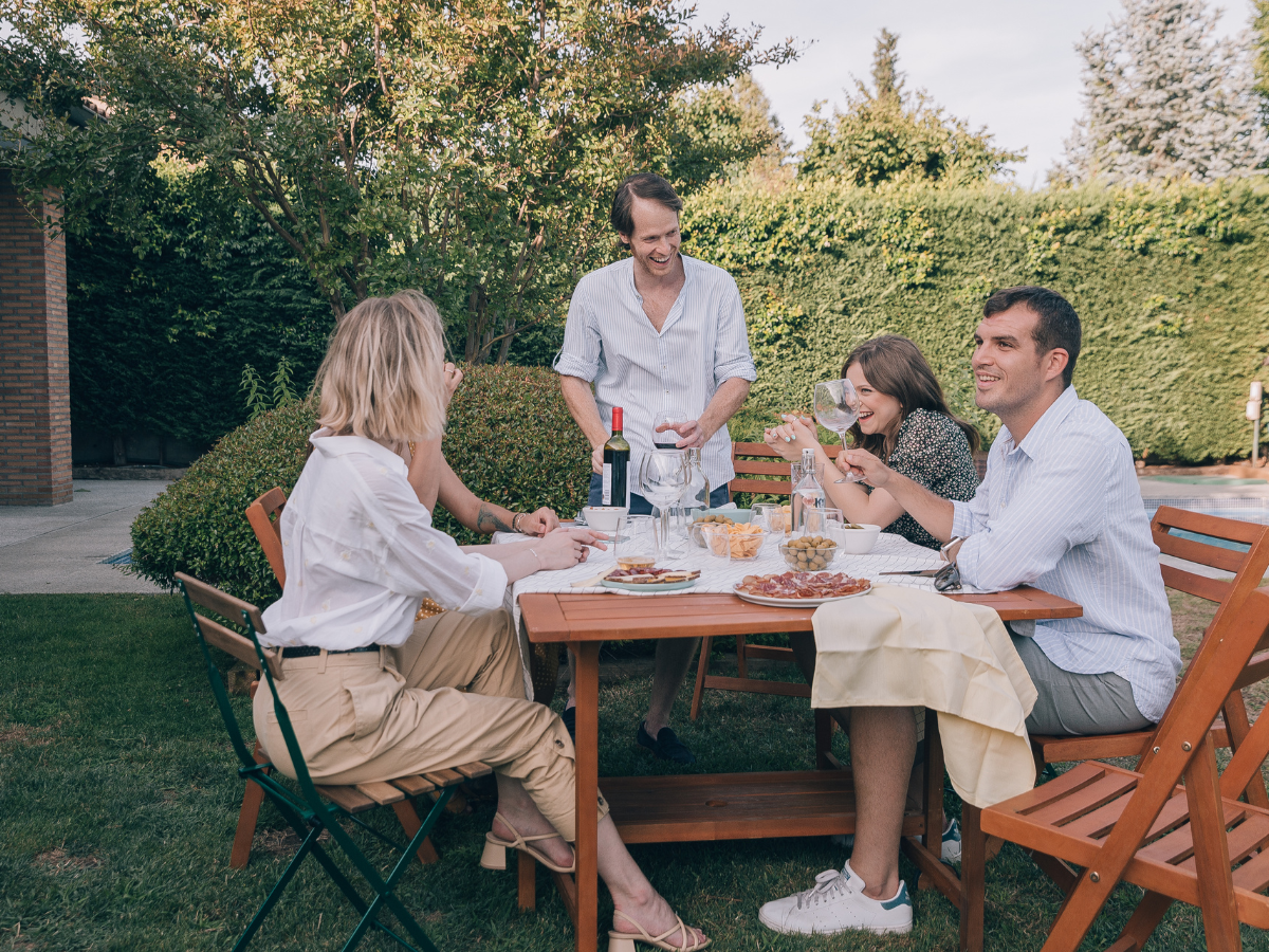 Friends laughing and sharing drinks at an outdoor table, showing how printable games can add fun and connection to any casual gathering.